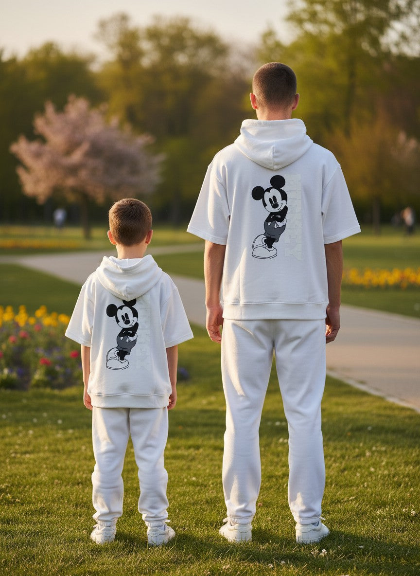 Two children wearing matching white outfits with a Mickey Mouse design in a park. Antler, Monza Outlet, Monza Fashion, Shein Outlet