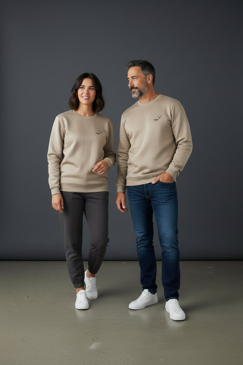Man and woman wearing matching beige sweatshirts and dark pants against a gray background. Antler, Monza Outlet, Monza Fashion, Shein Outlet