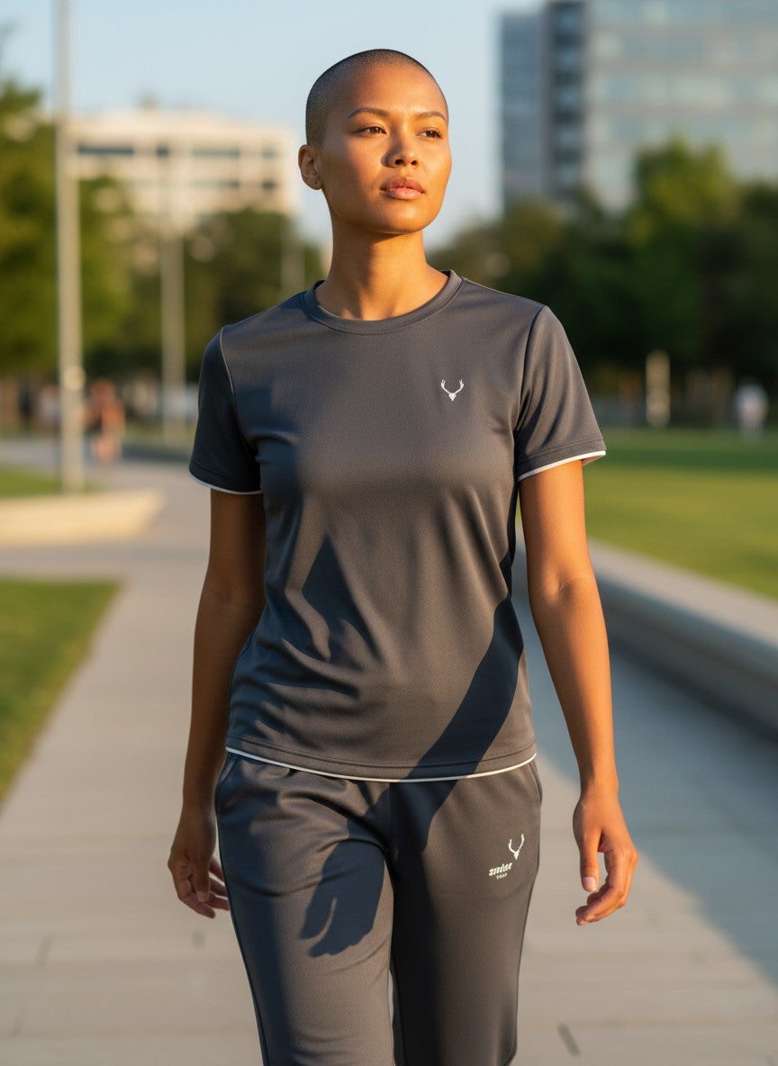 Person wearing a gray athletic outfit with a logo on a blurred outdoor background. Antler, Monza Outlet, Monza Fashion, Shein Outlet