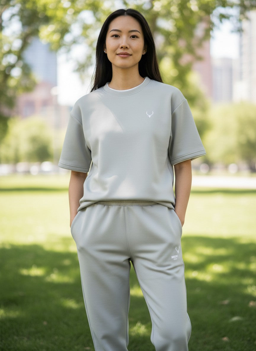 Person wearing a light gray outfit with a logo in an outdoor setting. Antler, Monza Outlet, Monza Fashion, Shein Outlet