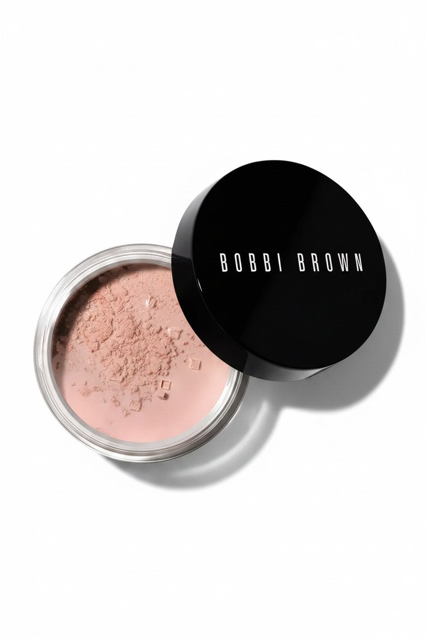 Bobbi Brown loose powder in a clear jar with its black lid leaning against it, photographed on a clean white background. Bobbi Brown, Monza Outlet, Monza Fashion, Shein Outlet