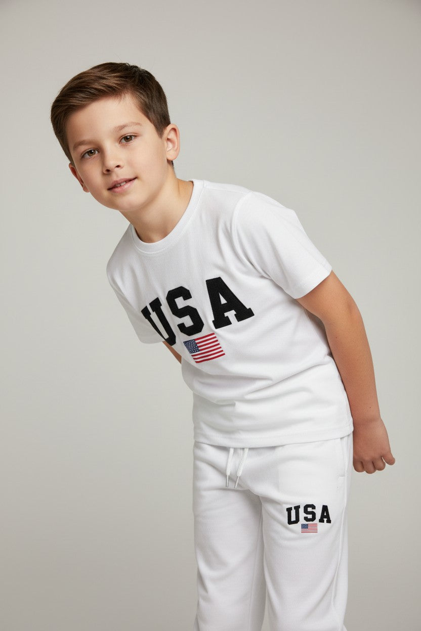Child wearing a white USA t-shirt and pants with an American flag on a gray background. Antler, Monza Outlet, Monza Fashion, Shein Outlet