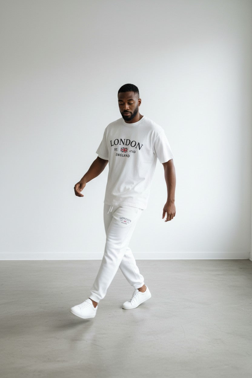 Man wearing a white London t-shirt and pants in a minimalistic setting. Antler, Monza Outlet, Monza Fashion, Shein Outlet