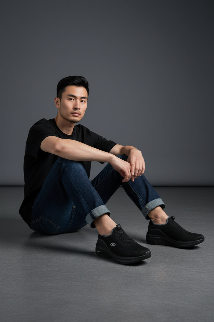 Man wearing black shoes sitting on a gray floor against a dark gray background. Maklinit, Monza Outlet, Monza Fashion, Shein Outlet