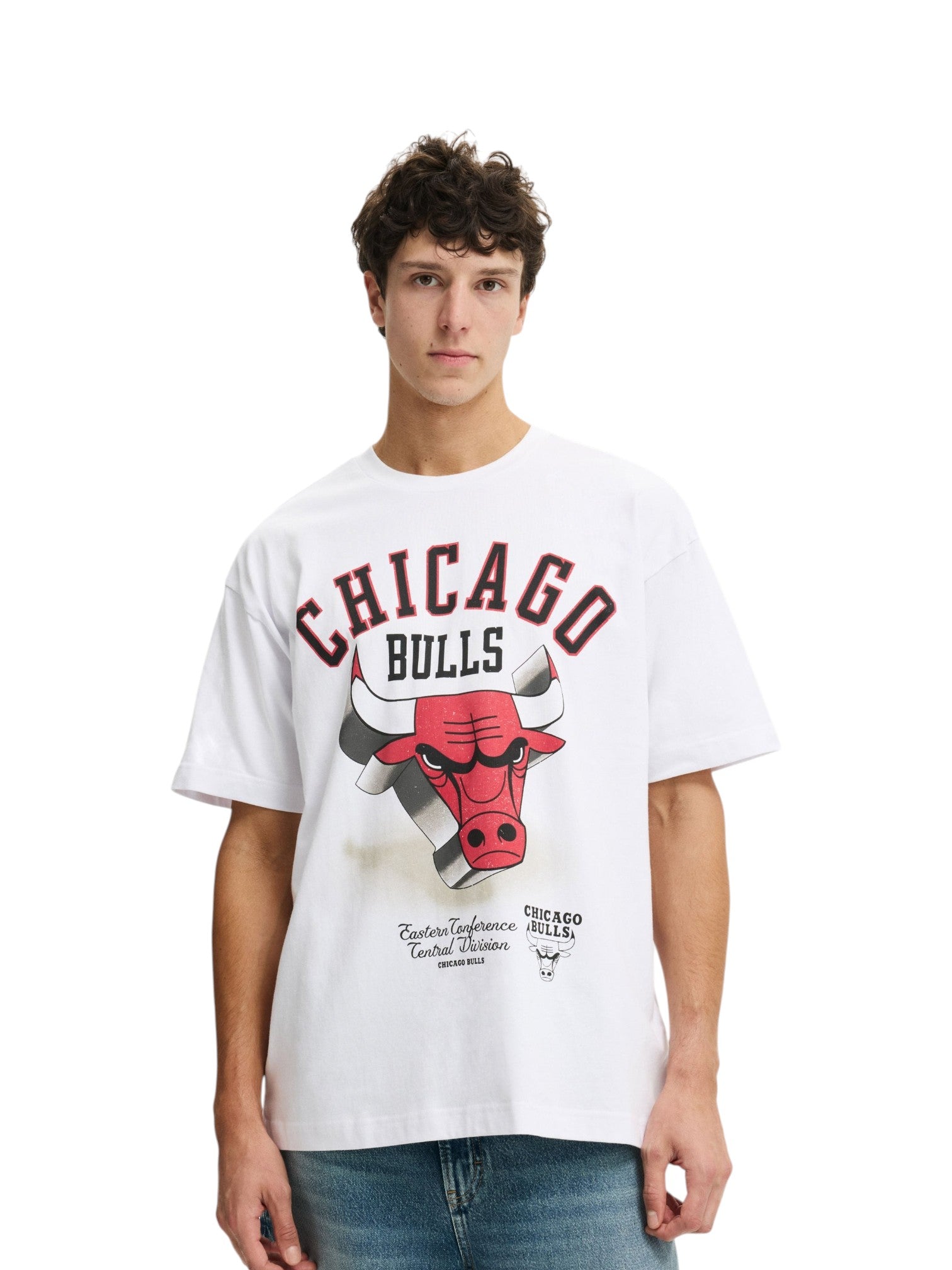 A young man wearing a white short-sleeve t-shirt with a large Chicago Bulls graphic on the front, paired with blue jeans, against a plain white background. NBA, Monza Outlet, Monza Fashion, Shein Outlet