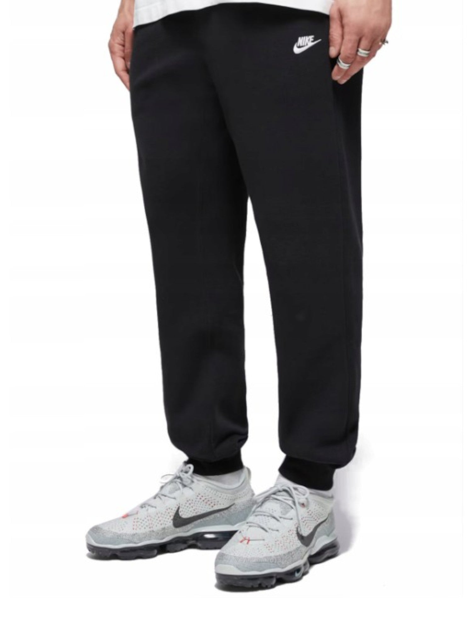 Person wearing black Nike sweatpants and gray Nike sneakers on a white background. Nike, Monza Outlet, Monza Fashion, Shein Outlet