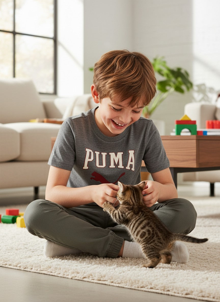 Child playing with a kitten on a carpeted floor in a living room. Puma, Monza Outlet, Monza Fashion, Shein Outlet