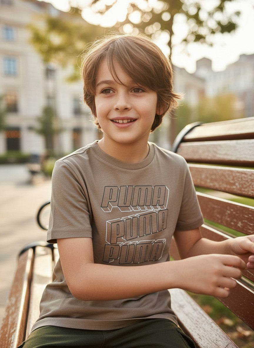 Child wearing a Puma t-shirt sitting on a bench outdoors. Puma, Monza Outlet, Monza Fashion, Shein Outlet