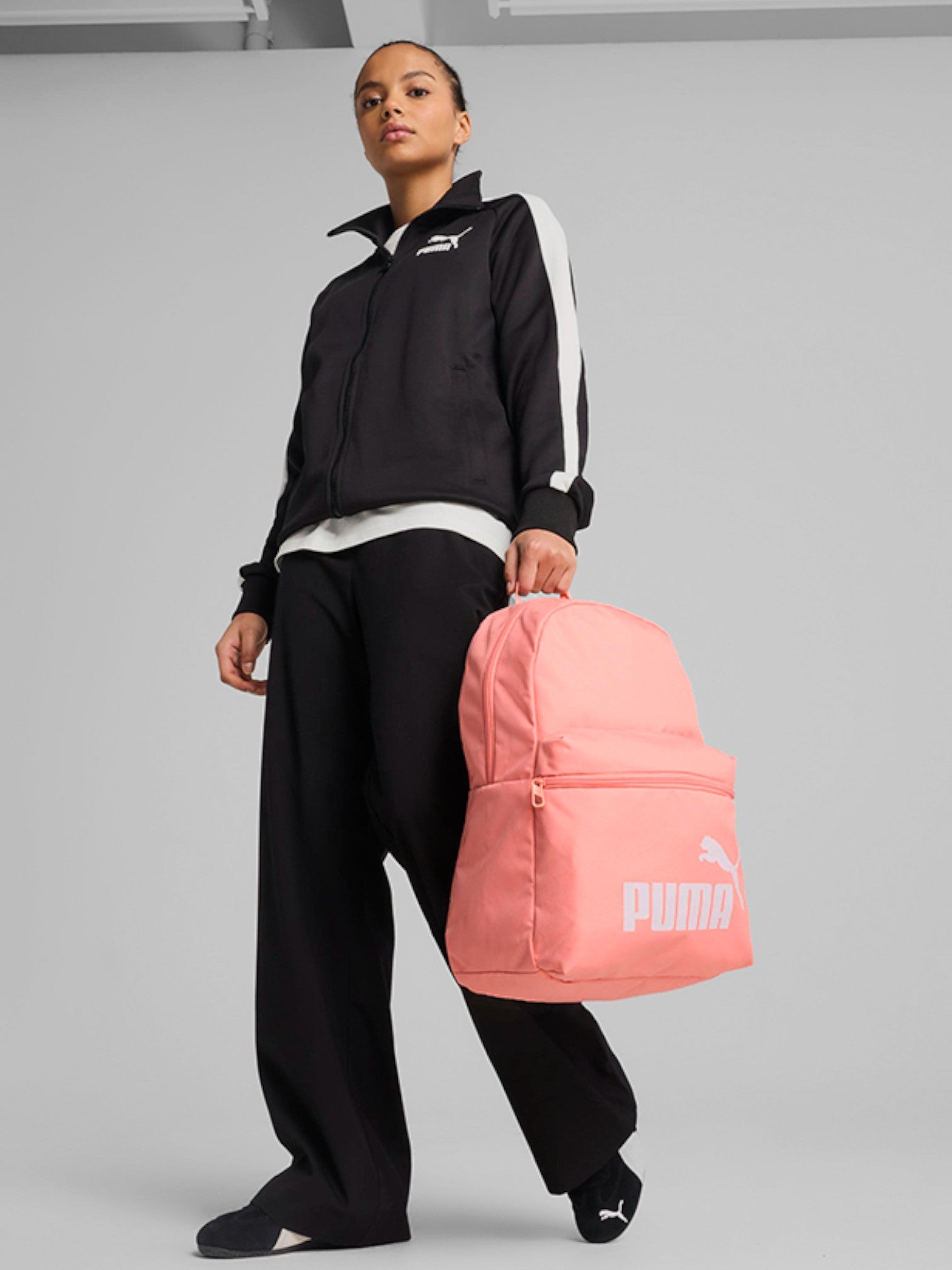Person holding a pink Puma backpack against a gray background. Puma, Monza Outlet, Monza Fashion, Shein Outlet