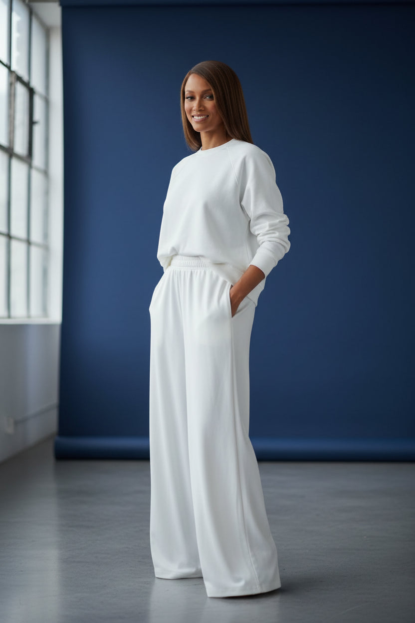 Woman wearing a white outfit standing against a blue wall. Roncato, Monza Outlet, Monza Fashion, Shein Outlet