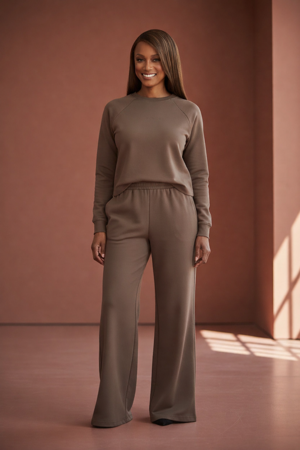 Woman wearing a brown outfit standing against a warm-toned wall. Roncato, Monza Outlet, Monza Fashion, Shein Outlet