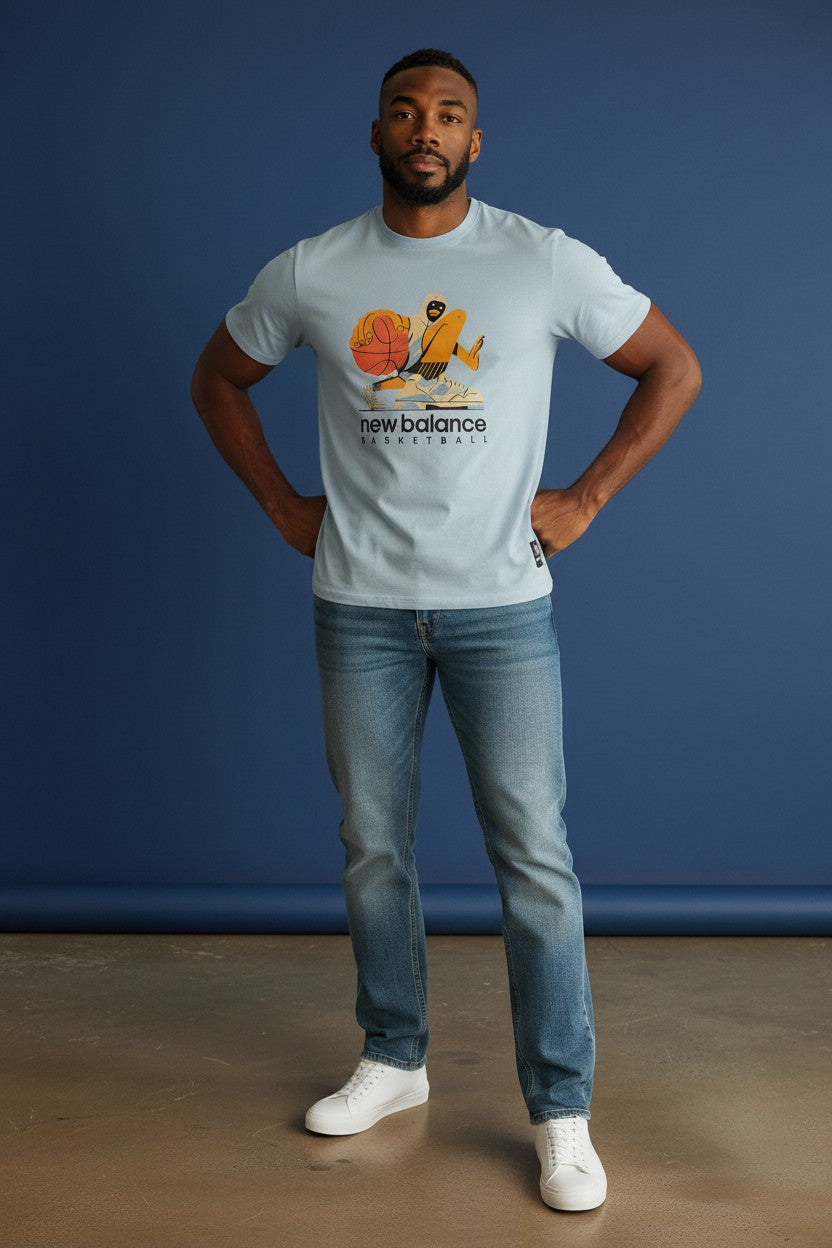 Man wearing a light blue t-shirt with a logo and text, standing against a blue background. New Balance, Monza Outlet, Monza Fashion, Shein Outlet