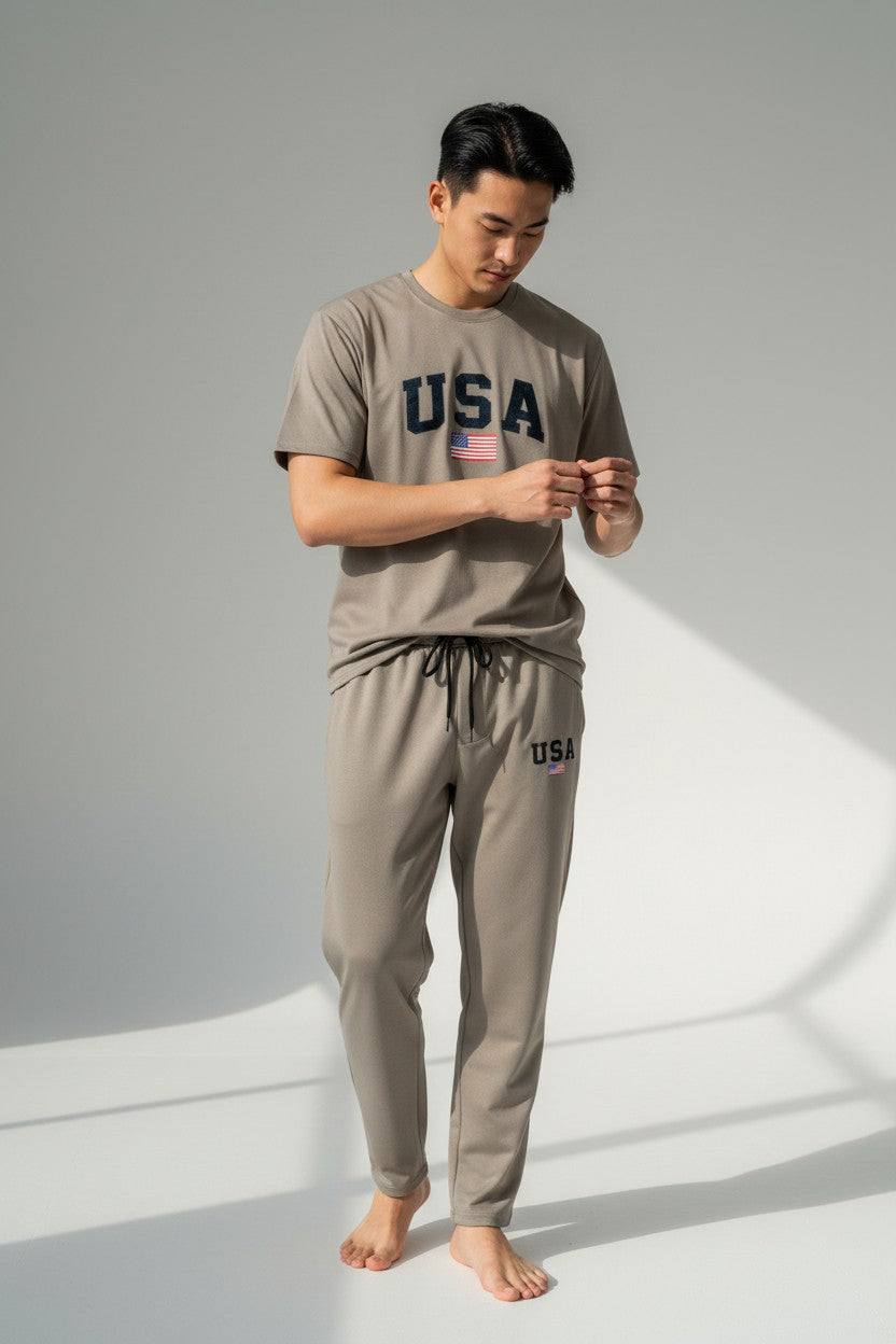 Man wearing a matching beige t-shirt and pants with USA text on a gray background. Antler, Monza Outlet, Monza Fashion, Shein Outlet