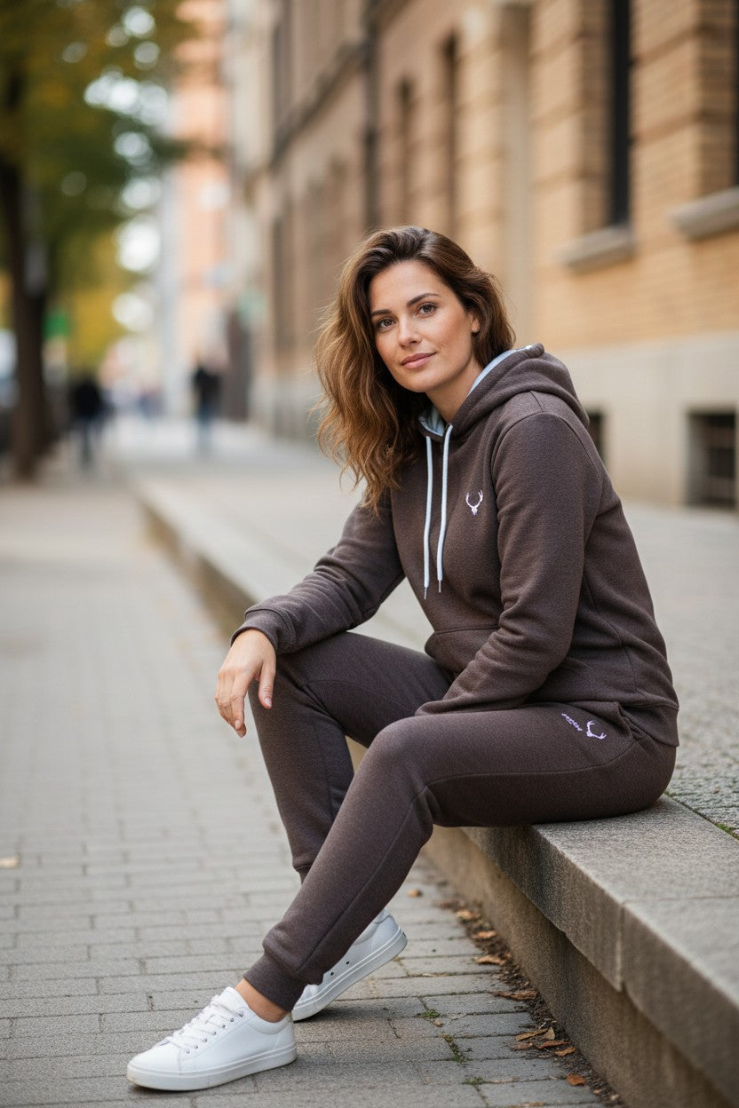 Woman sitting on a city street wearing a brown tracksuit with white sneakers. Antler, Monza Outlet, Monza Fashion, Shein Outlet