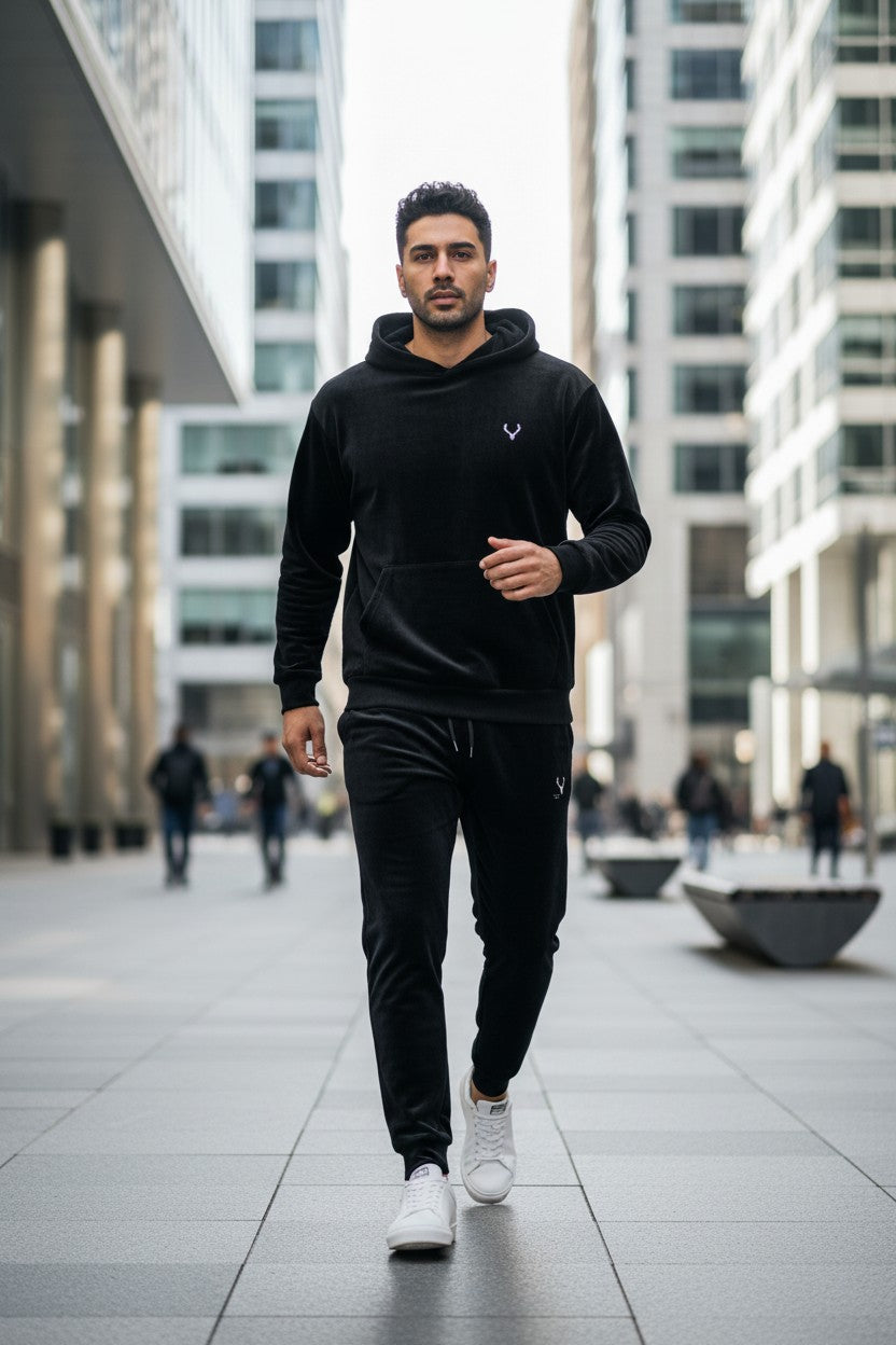 Man wearing a black hoodie and pants walking in an urban setting. Antler, Monza Outlet, Monza Fashion, Shein Outlet