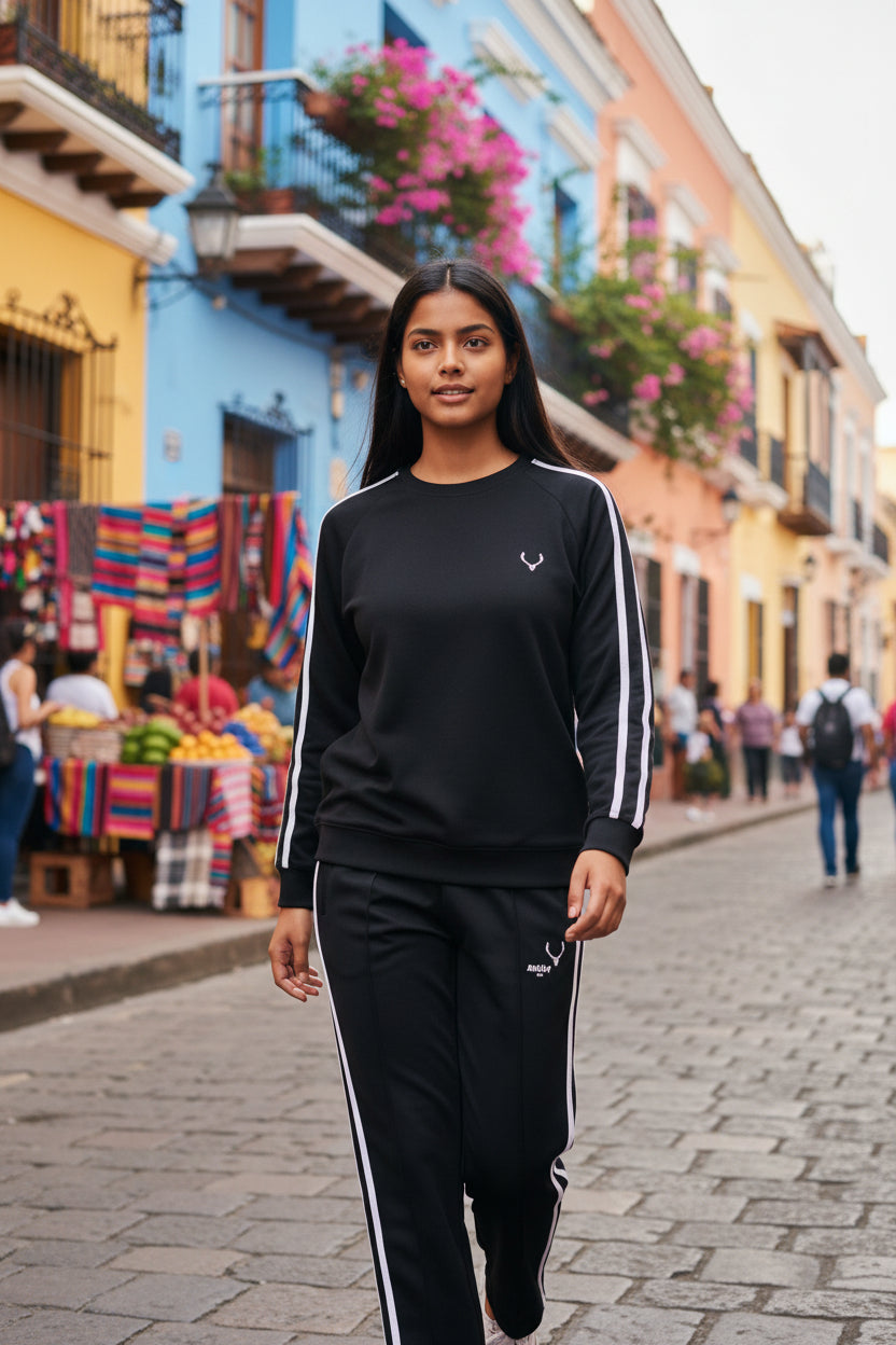 Woman in black tracksuit standing on a street with colorful buildings and market stalls in the background. Antler, Monza Outlet, Monza Fashion, Shein Outlet