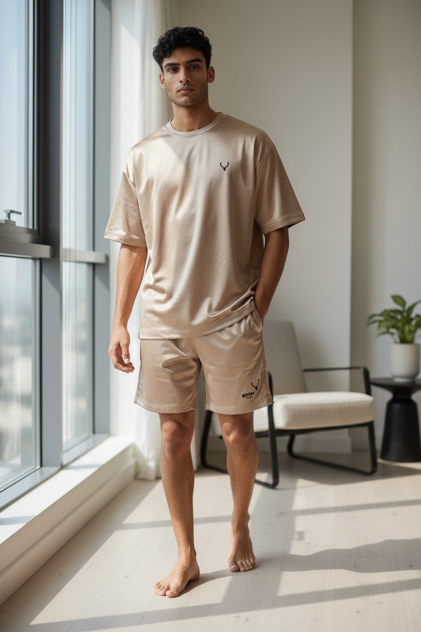 Man wearing a beige t-shirt and shorts standing in a modern room with large windows. Antler, Monza Outlet, Monza Fashion, Shein Outlet