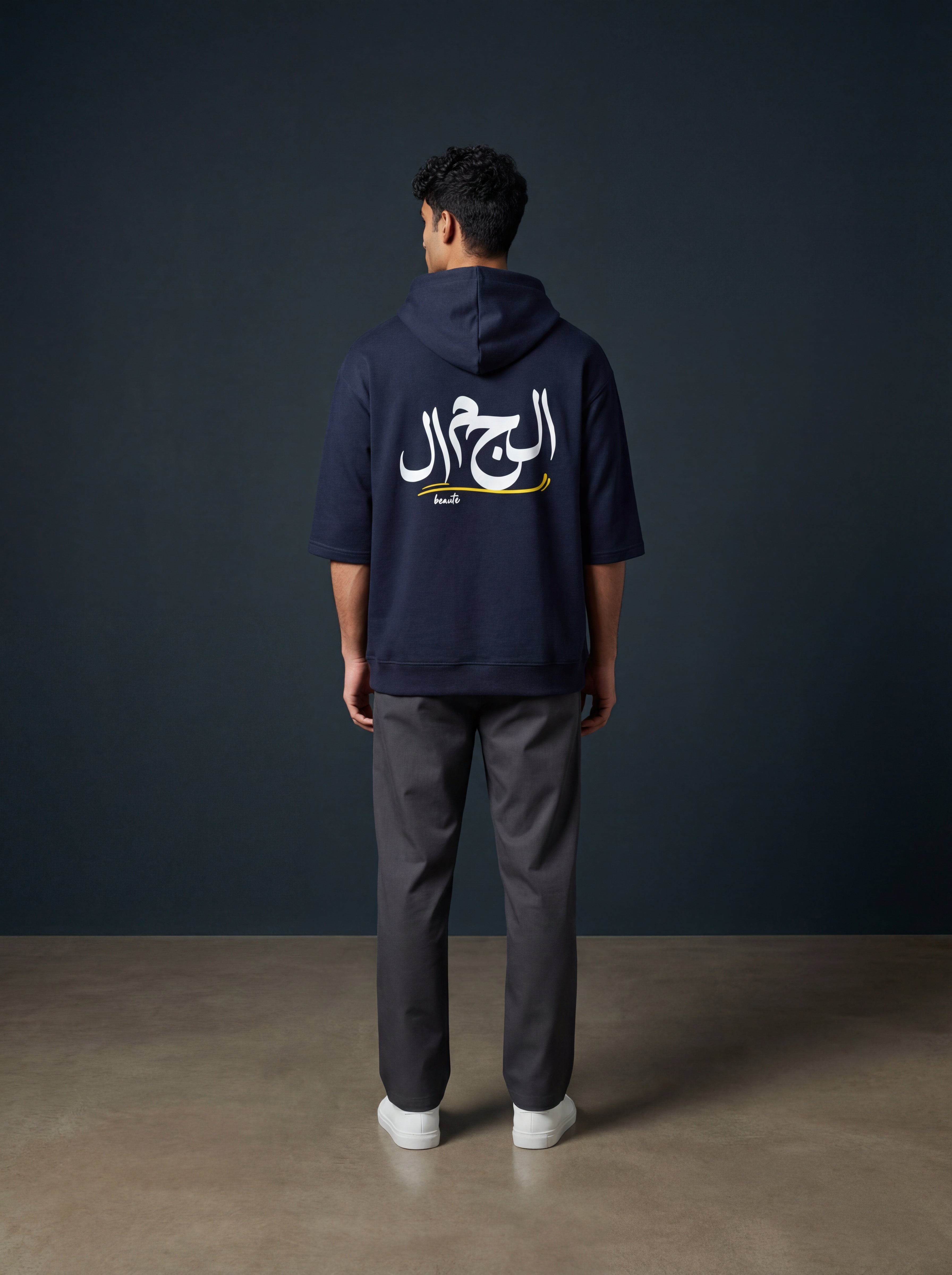 Person wearing a navy hoodie with Arabic text on the back against a dark gray background. Monza Antler Men, Monza Outlet, Monza Fashion, Shein Outlet