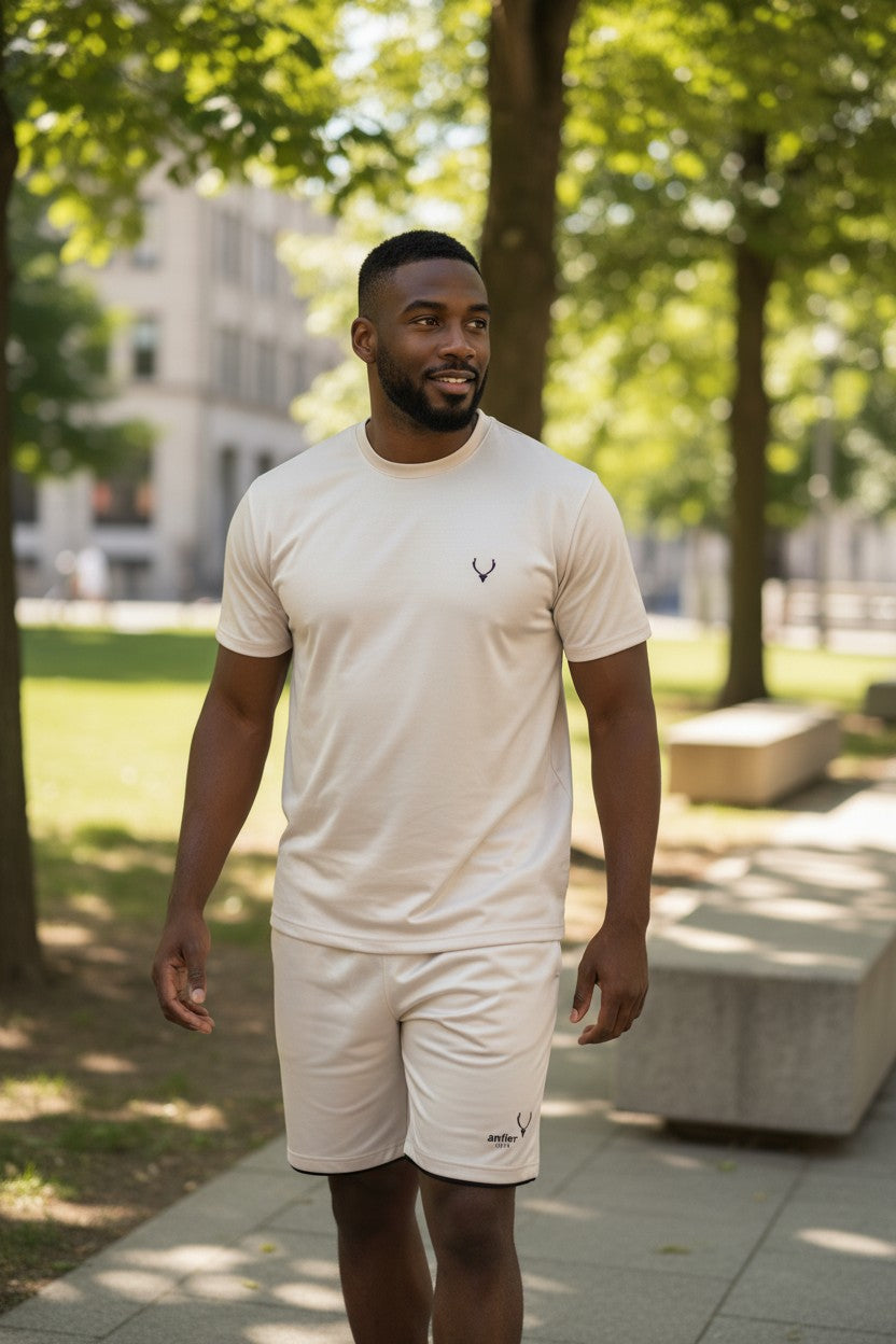 Man wearing a white t-shirt and shorts with a logo, standing in a park. Antler, Monza Outlet, Monza Fashion, Shein Outlet
