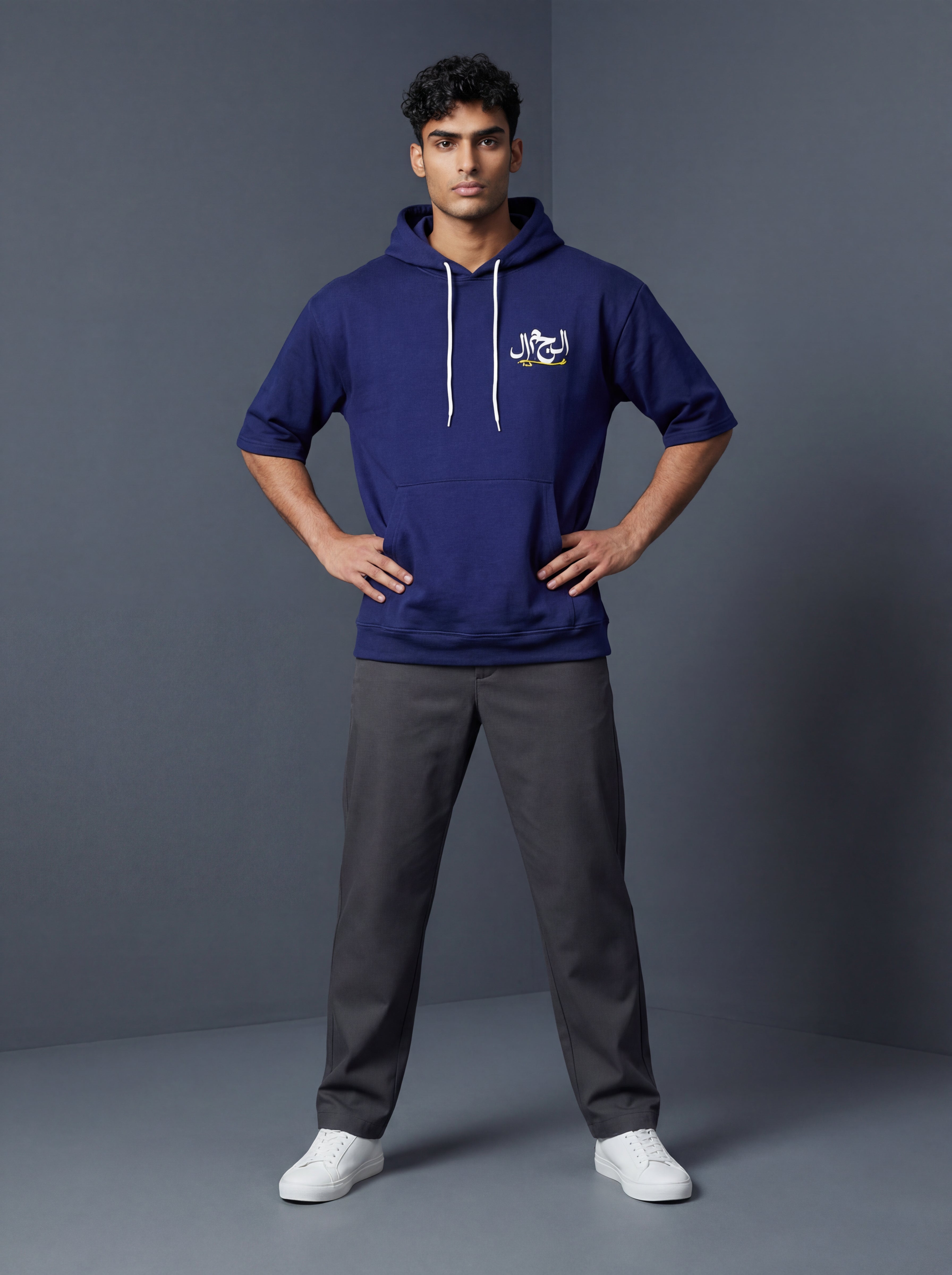 Man wearing a blue hoodie with a logo and gray pants on a gray background. Monza Antler Men, Monza Outlet, Monza Fashion, Shein Outlet