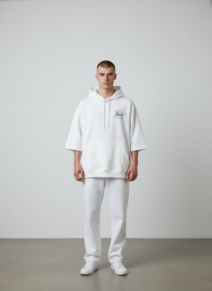 Person wearing a white hoodie with a logo and white pants on a plain background. Antler, Monza Outlet, Monza Fashion, Shein Outlet