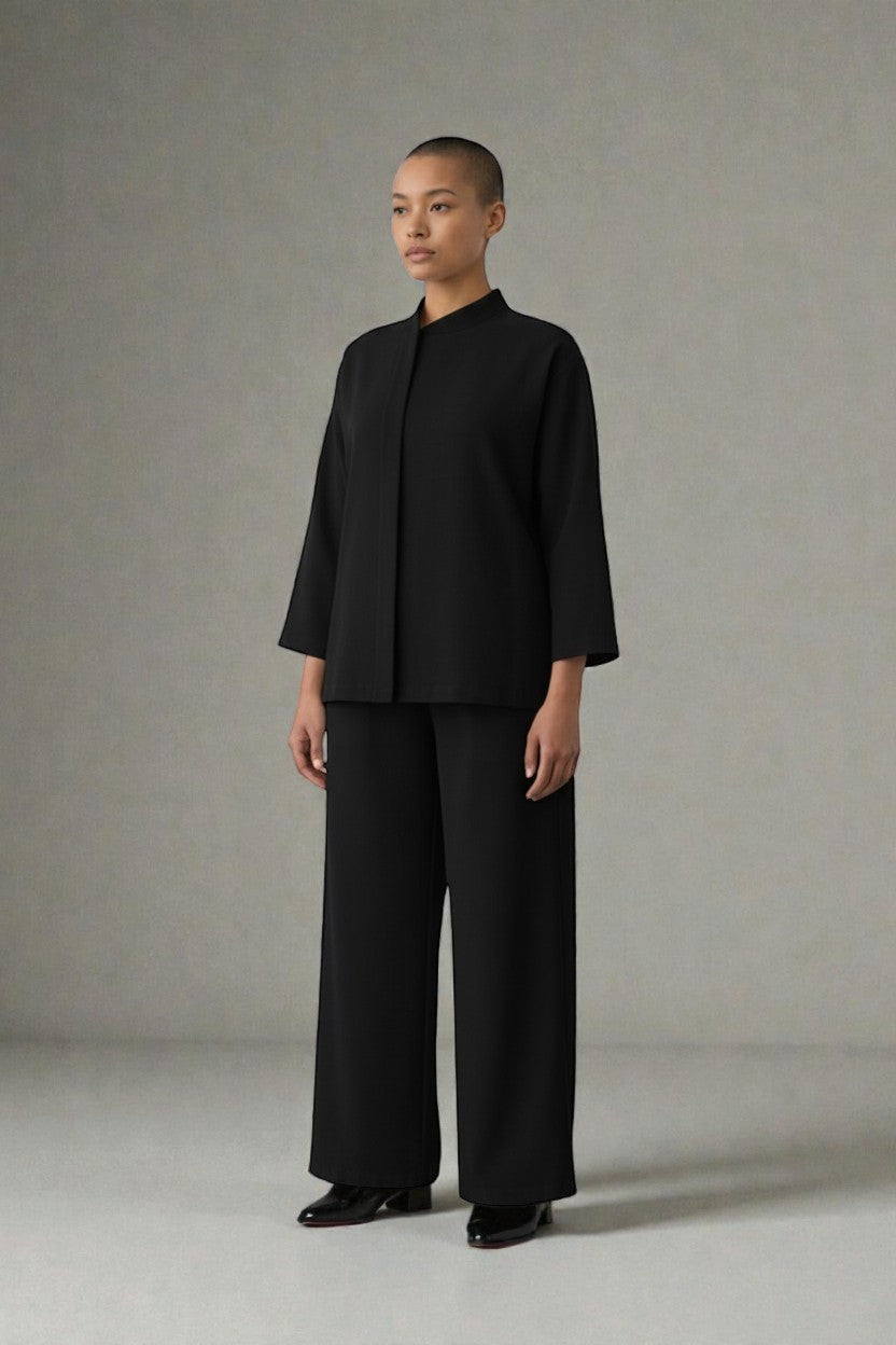 Person wearing a black suit standing against a plain background. Antler, Monza Outlet, Monza Fashion, Shein Outlet