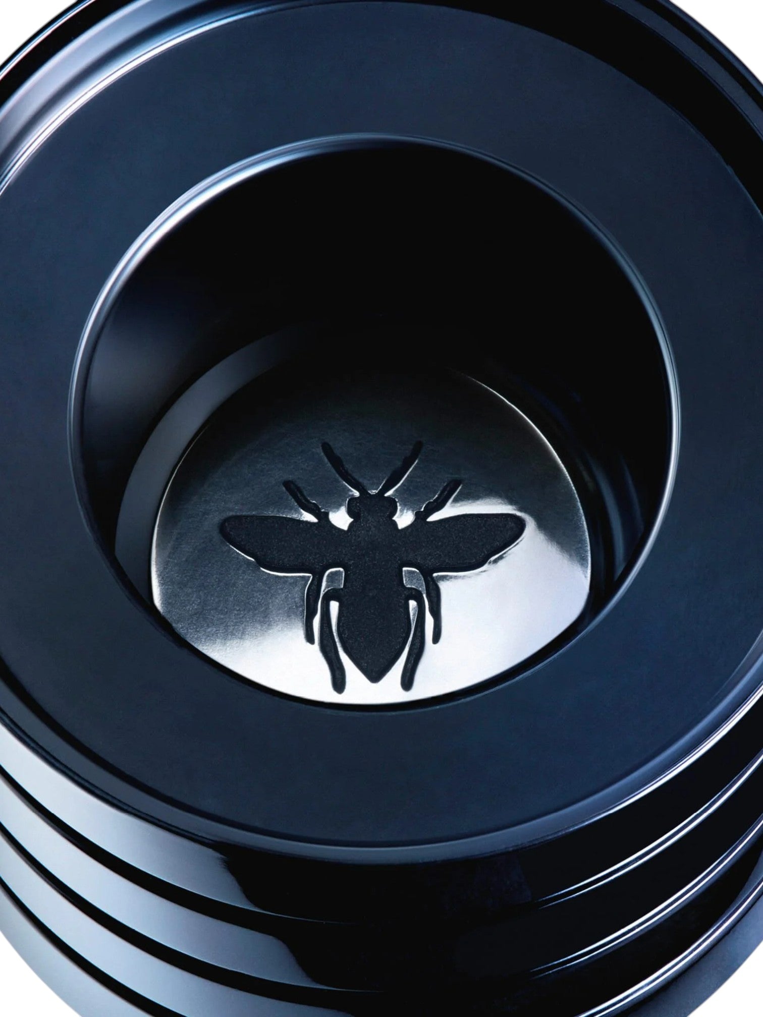 Close-up of a black metal component with a bee emblem on a white background, Christian Dior, Monza Outlet, Monza Fashion, Shein Outlet