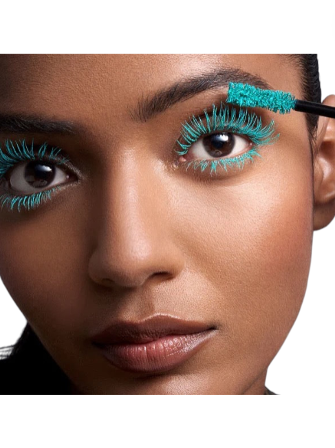 Woman applying turquoise eyelashes with a brush on a white background. Pat McGrath Labs Monza Outlet