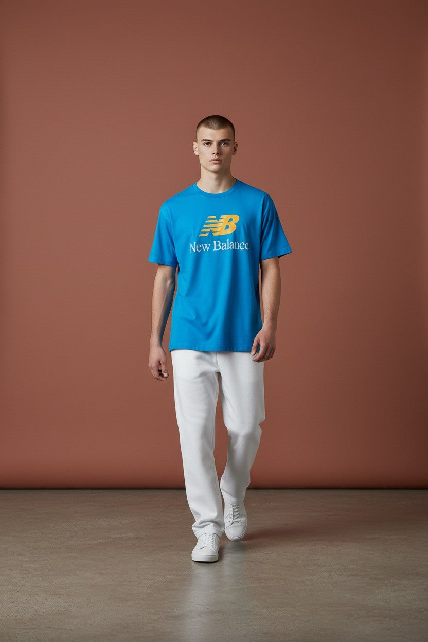 Man wearing a blue New Balance t-shirt against a brown background. New Balance, Monza Outlet, Monza Fashion, Shein Outlet