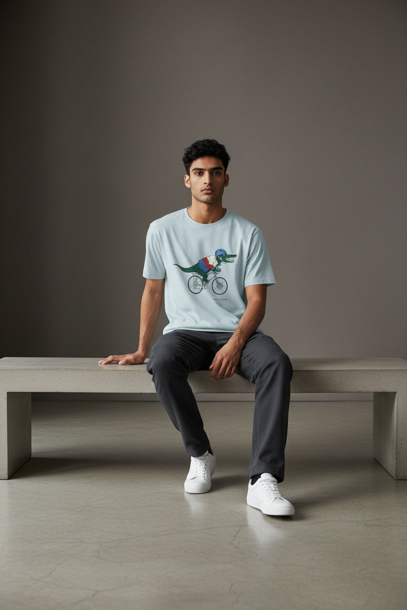 Man sitting on a bench wearing a light blue t-shirt with a graphic design. Lacoste, Monza Outlet, Monza Fashion, Shein Outlet