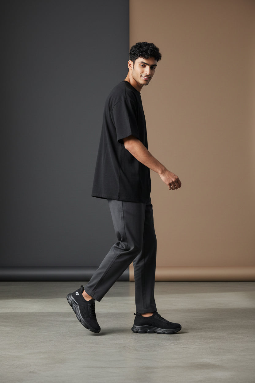 Man wearing a black outfit walking in a minimalistic setting. Maklinit, Monza Outlet, Monza Fashion, Shein Outlet