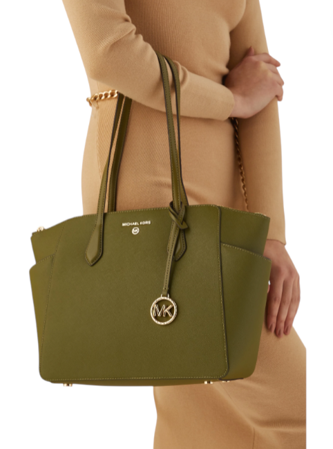 Green handbag with a brand logo held by a person wearing a beige coat. monza outlet, Shein outlet, monza fashion