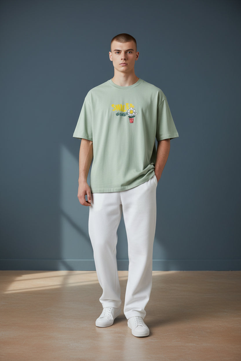 Man wearing a green t-shirt with a graphic design against a blue wall. Monza Outlet, Monza Fashion, Shein Outlet