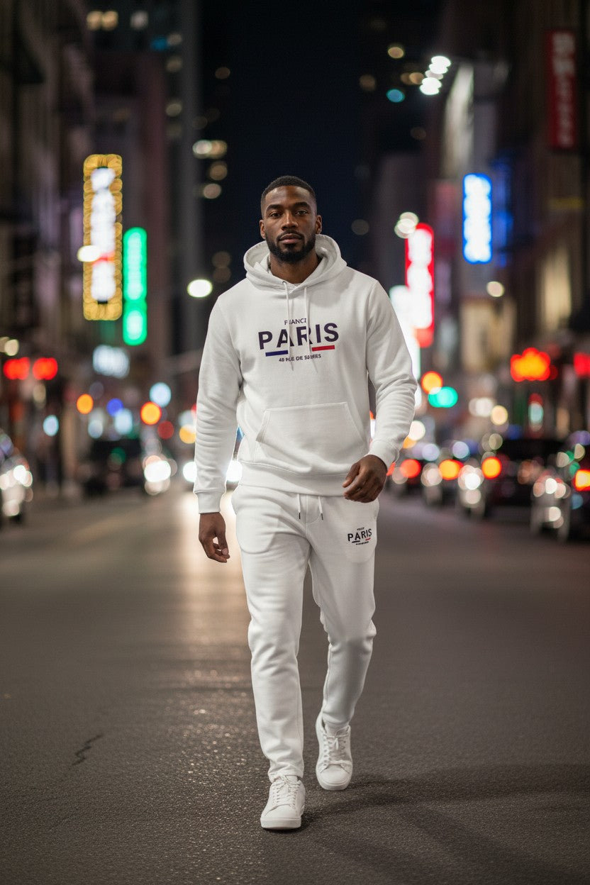 Man in a white PARIS hoodie and pants walking on a city street at night. Antler, Monza Outlet, Monza Fashion, Shein Outlet