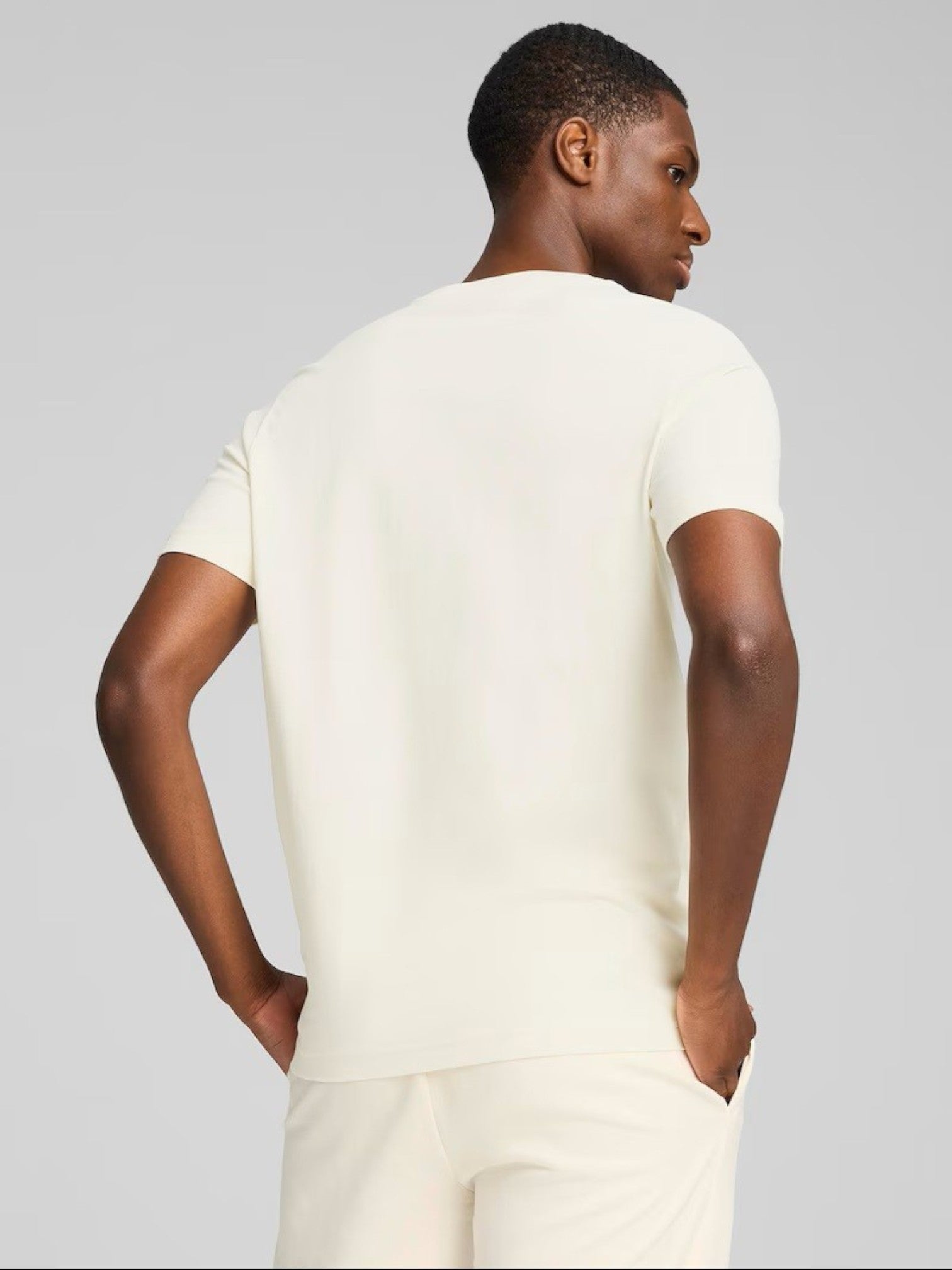 Person wearing a white t-shirt and pants against a gray background. Puma, Monza Outlet, Monza Fashion, Shein Outlet