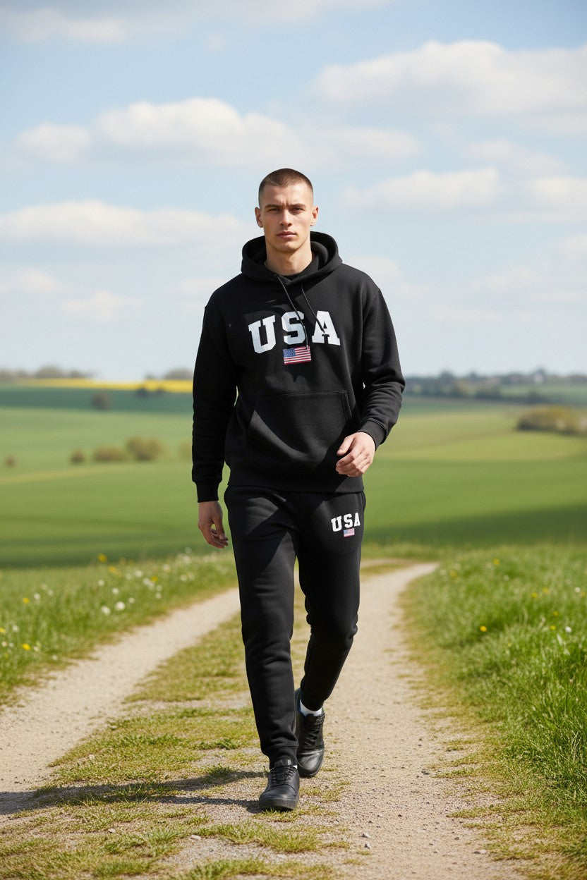 Man wearing a black hoodie with USA printed on it, walking on a path in a field. Antler, Monza Outlet, Monza Fashion, Shein Outlet