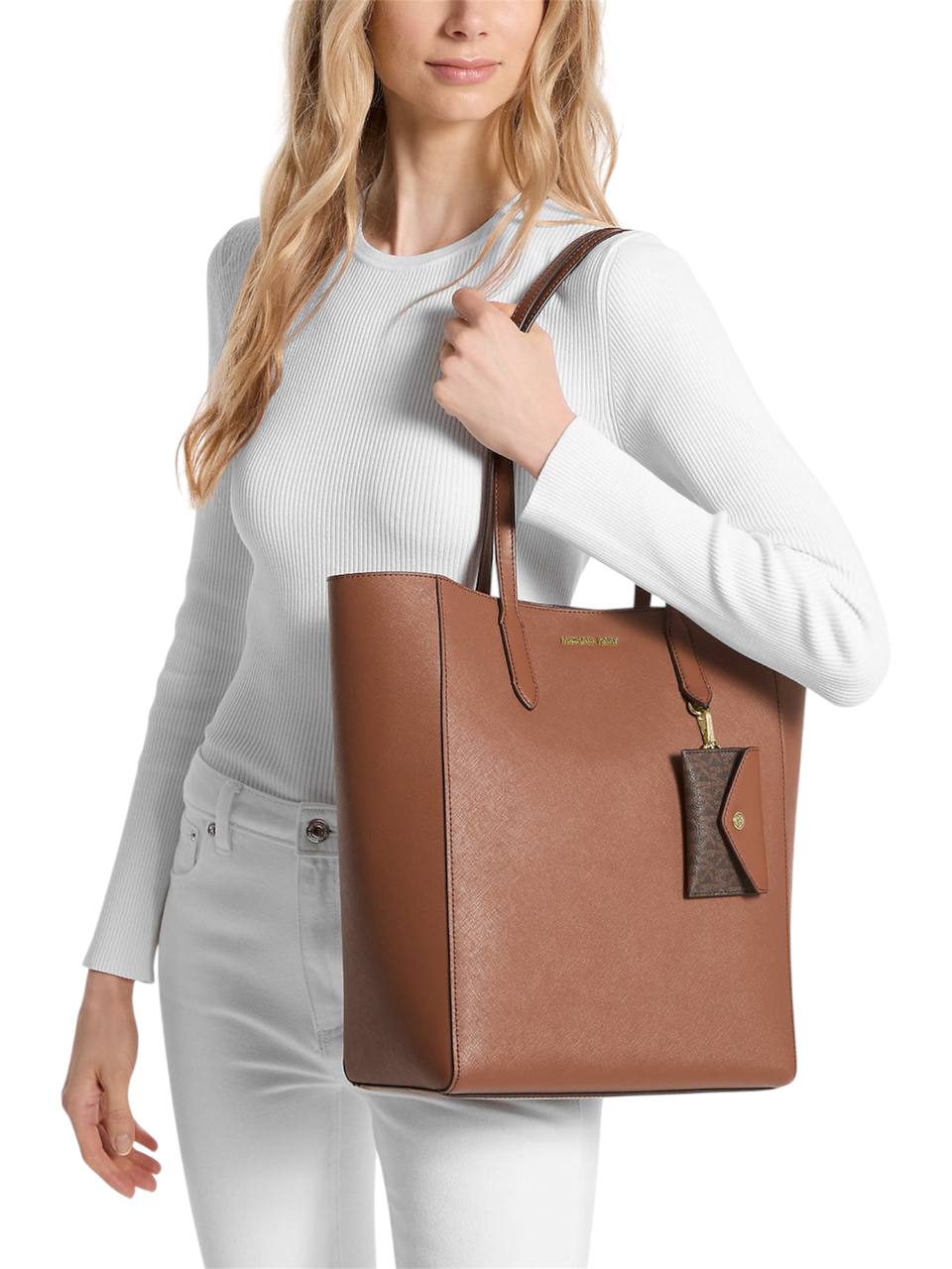 Woman holding a brown tote bag with a brand logo on a white background Michael Kors Monza Outlet
