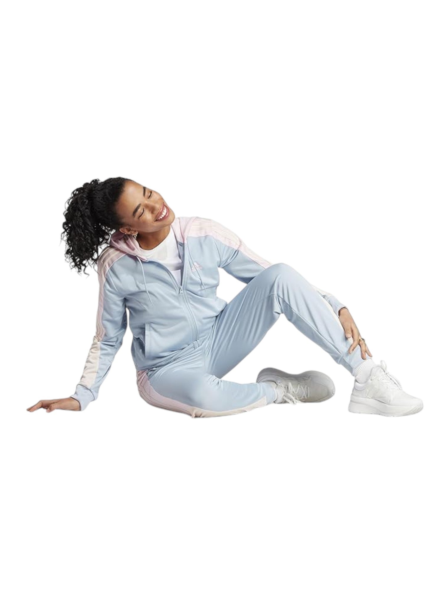 Woman sitting on a white background wearing a light blue tracksuit. Adidas, Monza Outlet, Monza Fashion, Shein Outlet