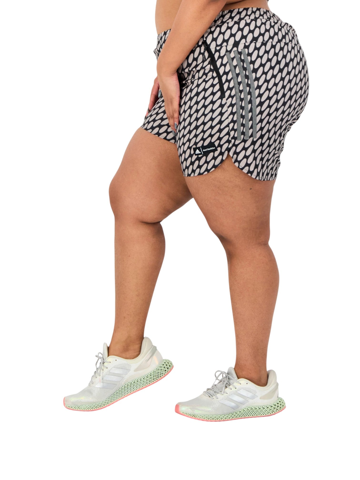 Person wearing black and white patterned shorts with white sneakers on a white background. Adidas, Monza Outlet, Monza Fashion, Shein Outlet