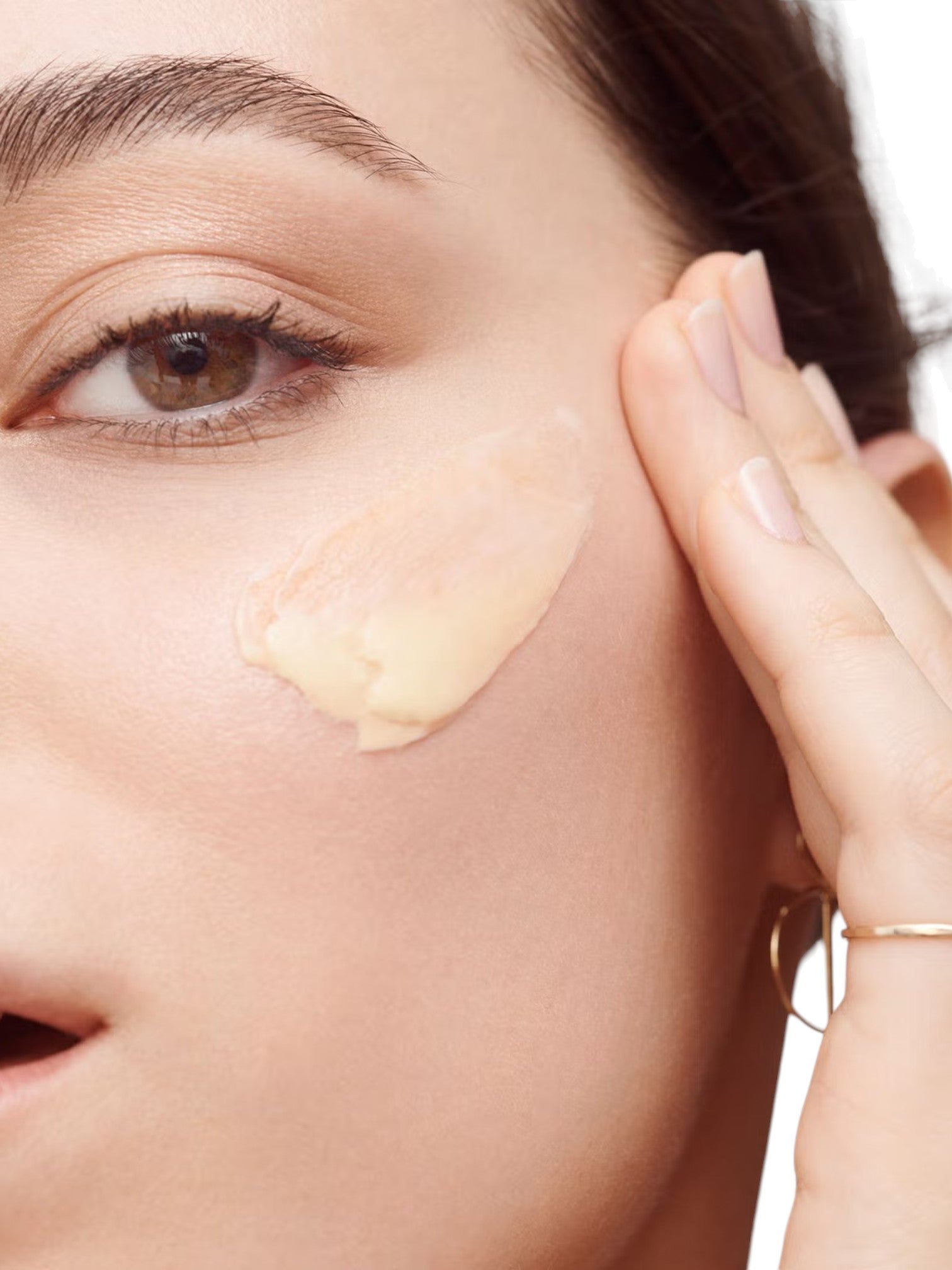 Close-up of a woman applying cream to her face with a hand. Bobbi Brown, Monza Outlet, Monza Fashion, Shein Outlet