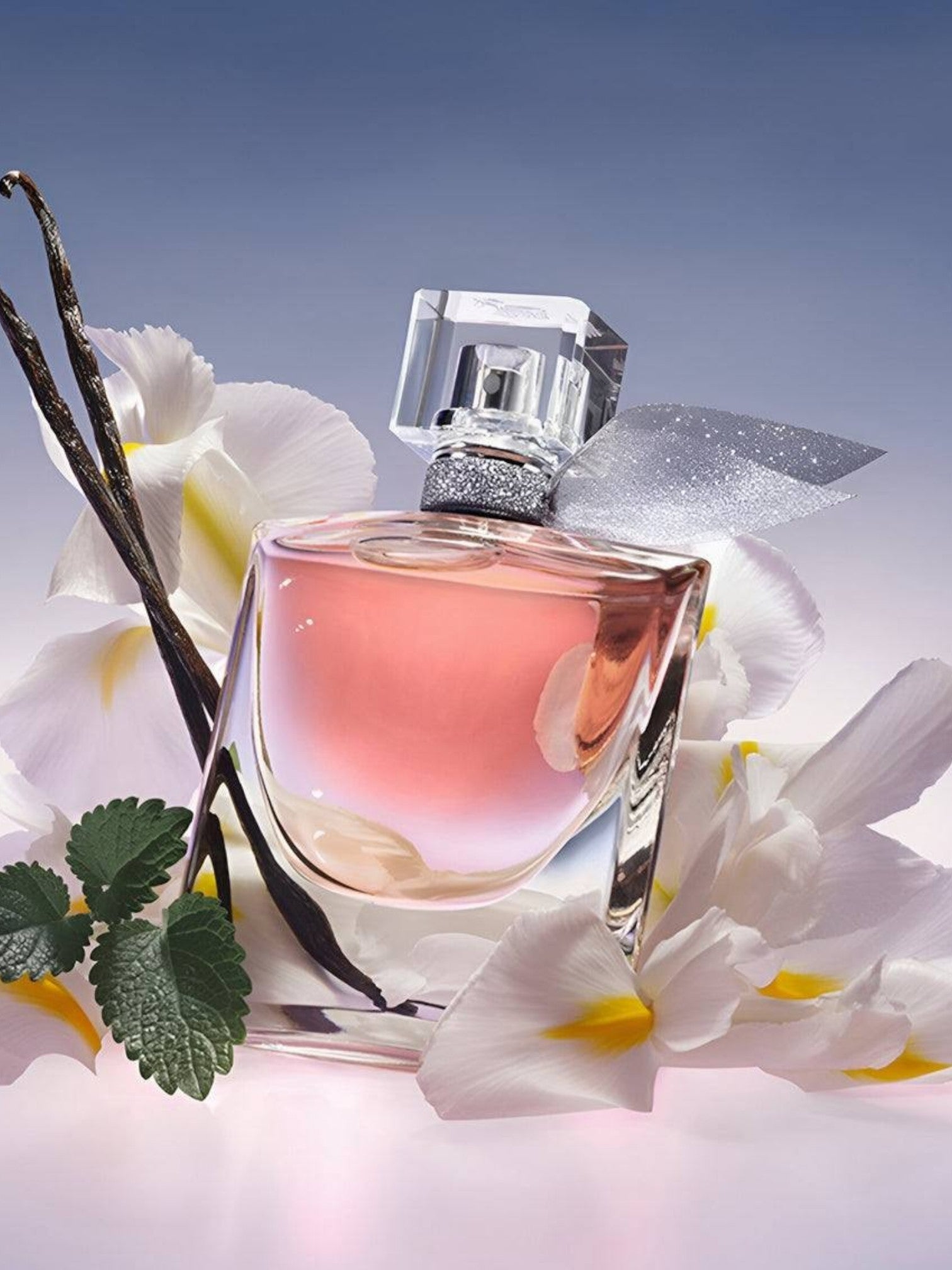 Perfume bottle with flowers and vanilla bean on a light background. Lancome, Monza Outlet, Monza Fashion, Shein Outlet