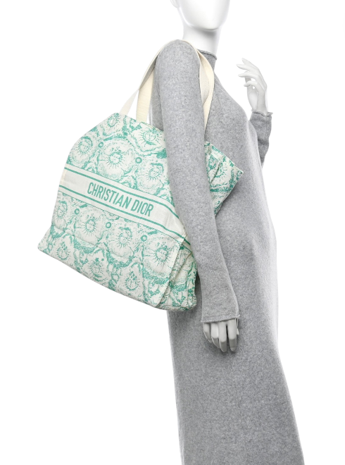 Mannequin wearing a gray outfit with a green and white patterned bag featuring Christian Dior branding. Dior Monza Outlet