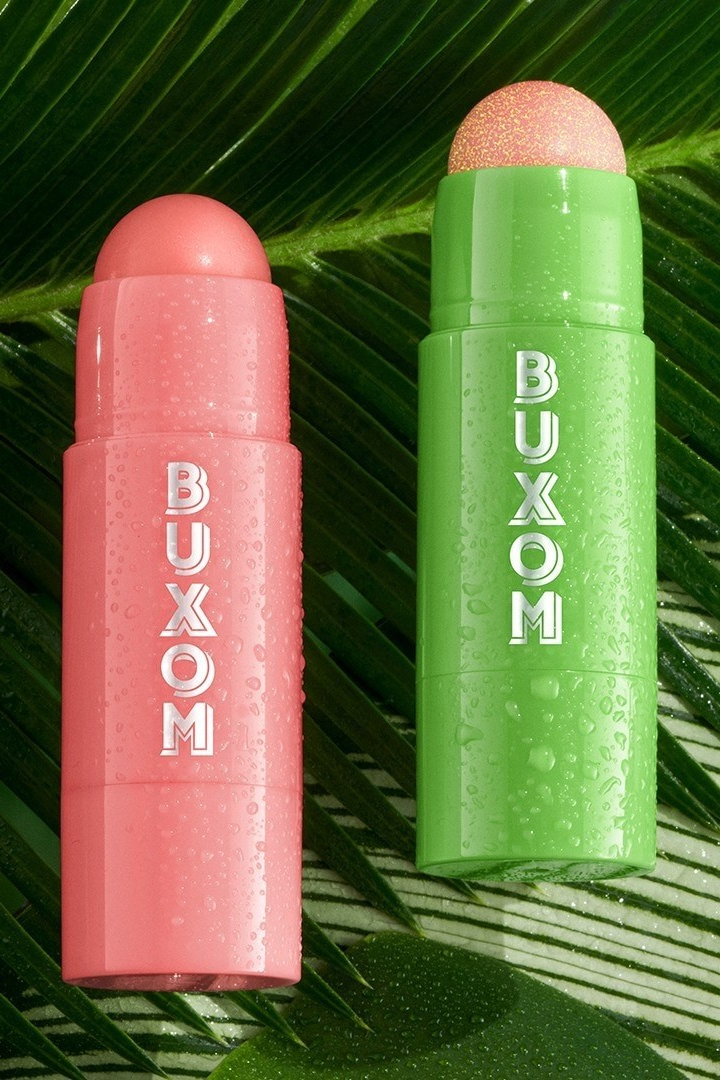 Two Buxom makeup sticks, one pink and one green, on a leaf background. Monza Outlet