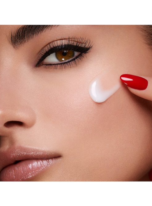 Close-up of a woman applying cream to her face with red nail polish. Monza Outlet