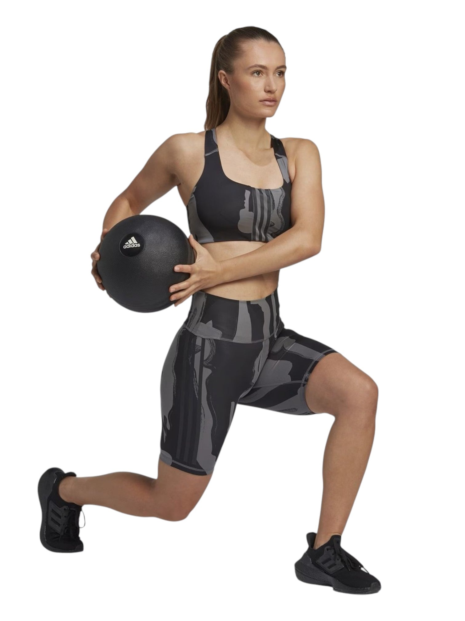 Woman exercising with a medicine ball wearing an Adidas outfit on a white background. Adidas, Monza Outlet, Monza Fashion, Shein Outlet