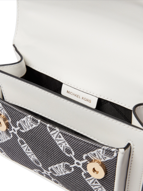 Close-up of a Michael Kors handbag with a white interior and patterned flap. Michael Kors Monza Outlet