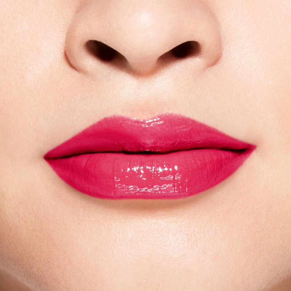 Close-up of a person wearing bright pink lipstick with a brand name.