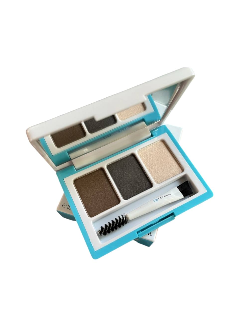 Open makeup palette with various shades of eyeshadow and a brush on a white background Clarins Monza Outlet