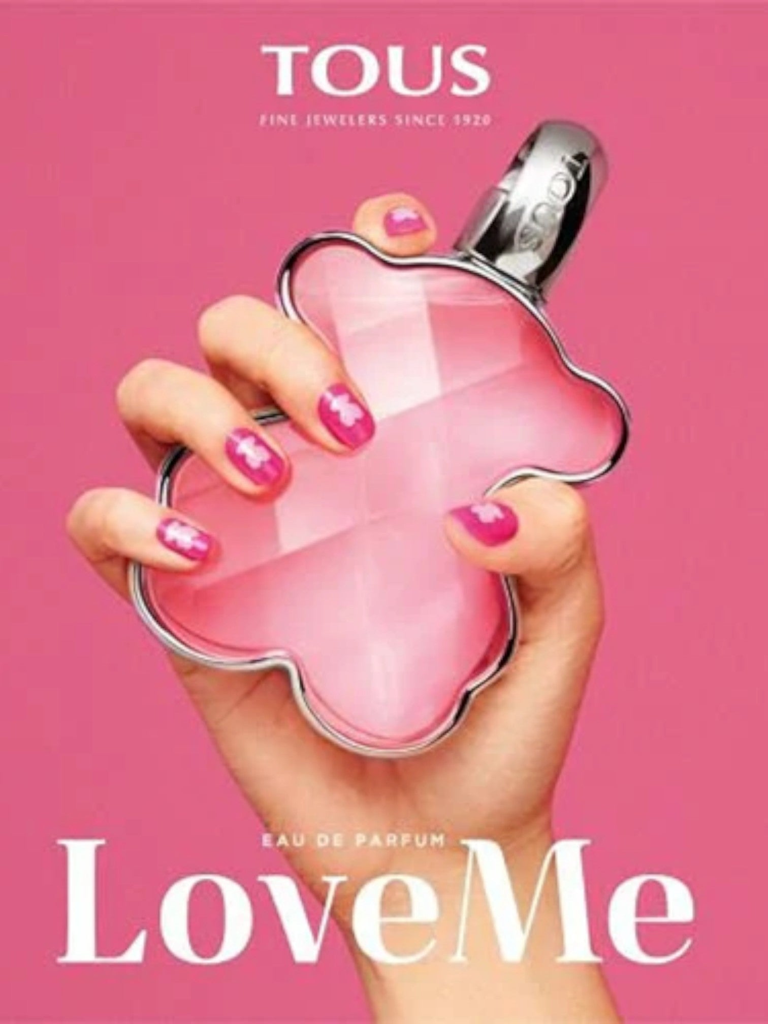 Pink perfume bottle held by a hand with TOUS Love Me branding on a pink background. Monza Outlet, Monza Fashion, Shein Outlet