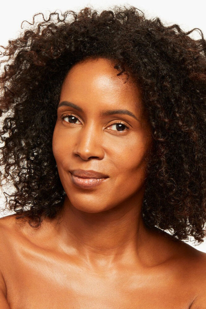 Woman with curly hair on a plain background Monza fashion outlet, monza outlet, shein outlet, shien outlet cosmetics, makeup, perfume